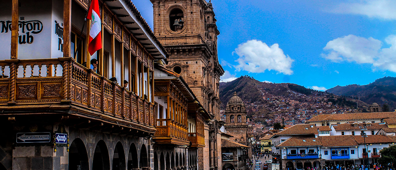 View of a colonial building with wooden balconies and church towers in Cusco, Peru.