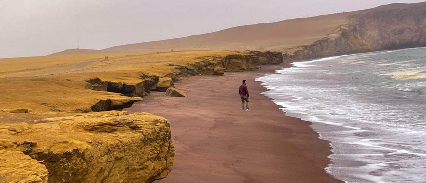 Red sand beach of Paracas with cliffs and ocean waves.