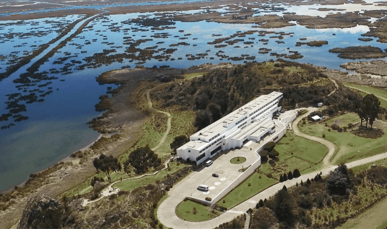 Aerial view of GHL Hotel Lago Titicaca surrounded by marshland and lake.