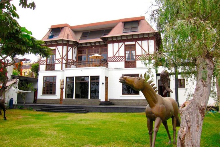 Large house with wooden beams and sculptures of animals in the garden.